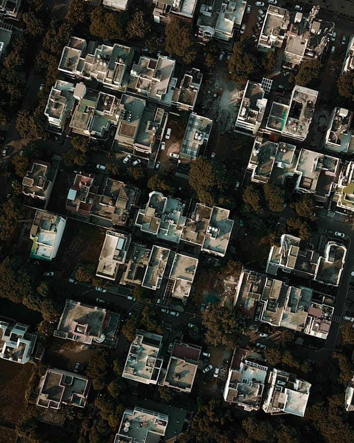 High-angle aerial view capturing residential buildings surrounded by greenery in an urban area during the day.